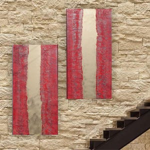 two large, abstract paintings hanging on a stone wall. The paintings are predominantly red and white, with a vertical line running through the center of each piece. The paintings are positioned next to a staircase, creating a visually striking contrast between the artwork and the architectural elements.
