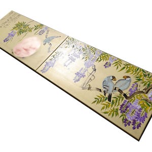 a wooden surface with a decorative design depicting birds and flowers.