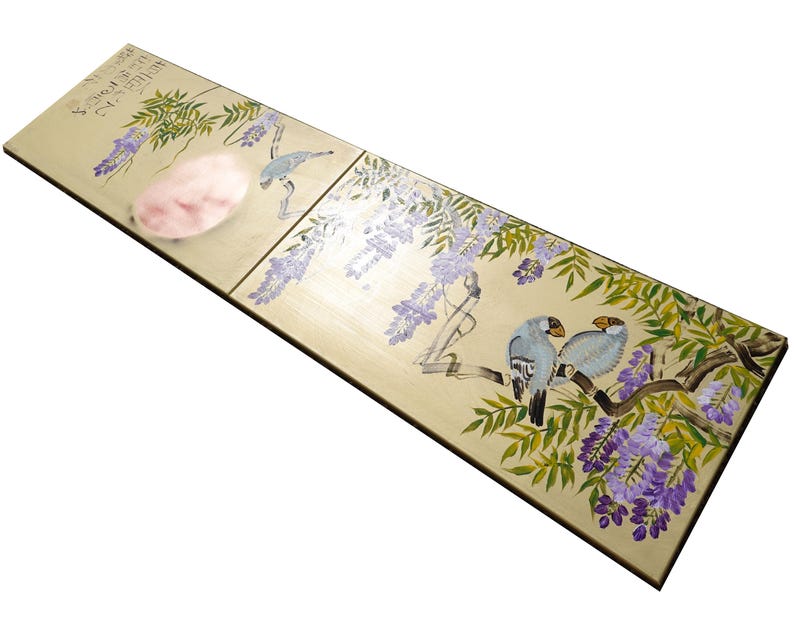 a wooden surface with a decorative design depicting birds and flowers.