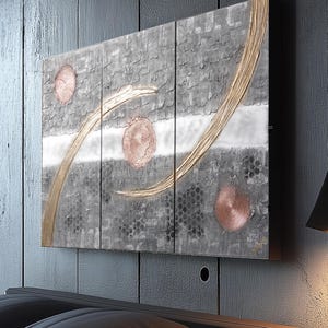 a modern art piece with a dark background and abstract design, including circles and lines, mounted on a wall above a bed.