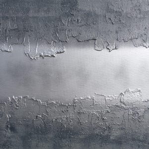 The image is a close-up of a textured surface with a metallic, metallic-looking appearance. The surface has a rough, uneven texture with a metallic sheen, giving it a metallic or metallic-like appearance.