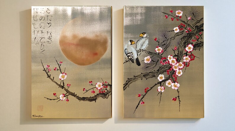 two paintings on a wall, depicting a large moon and cherry blossoms.