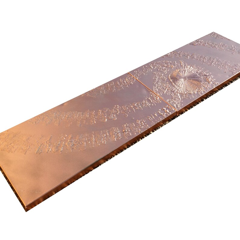 a metallic surface with a textured pattern, including a central circular design and a repeating pattern of lines and curves.