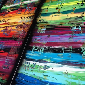The image is a vibrant and colorful abstract painting, featuring a variety of bold, overlapping brushstrokes in a range of bright colors including red, orange, yellow, green, blue, and purple. The painting appears to be a dynamic and energetic composition, with the different colors and brushstrokes creating a sense of movement and energy.