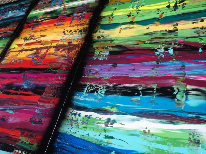 The image is a vibrant and colorful abstract painting, featuring a variety of bold, overlapping brushstrokes in a range of bright colors including red, orange, yellow, green, blue, and purple. The painting appears to be a dynamic and energetic composition, with the different colors and brushstrokes creating a sense of movement and energy.