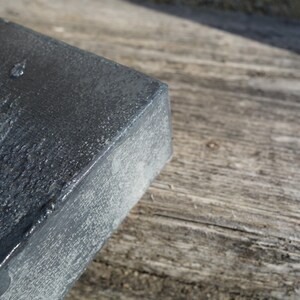 a close-up view of a dark, textured surface, possibly a metal or stone object, resting on a wooden surface.