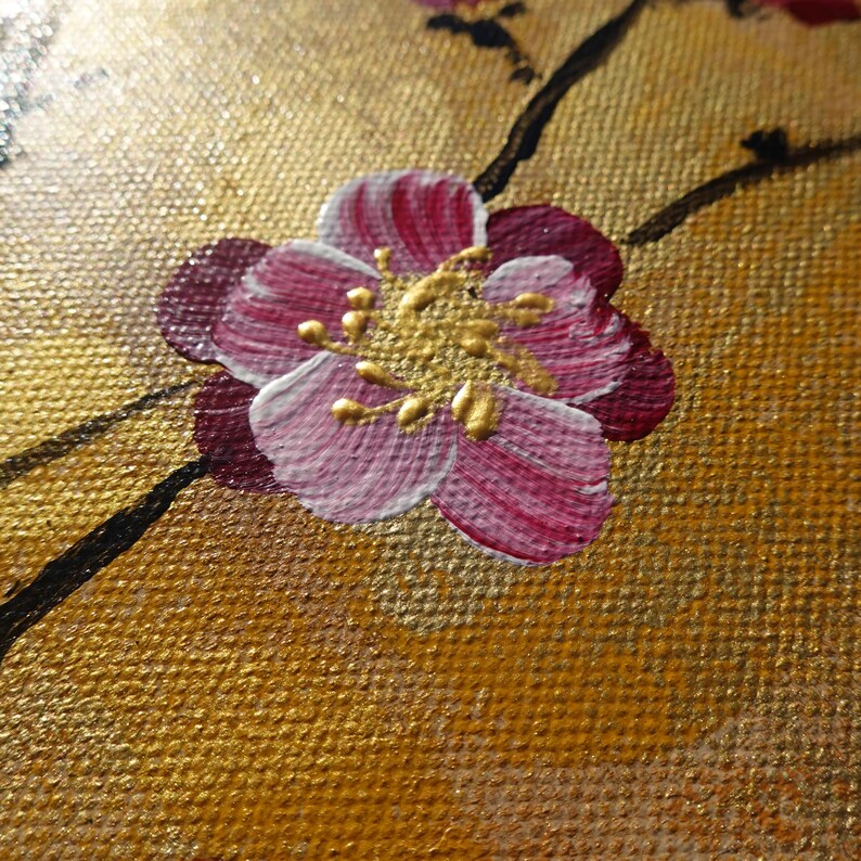 a close-up view of a vibrant pink flower with gold accents, set against a textured golden background.