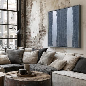 a cozy living room with a large window overlooking a cityscape. The room features a comfortable couch with a wooden coffee table in front of it, and a large abstract painting hanging on the wall above the couch.