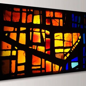 The image is a vibrant, abstract stained glass artwork with a colorful, geometric design. The glass pieces are arranged in a way that creates a striking visual effect, with warm and cool colors blending together to form a dynamic and eye-catching composition.