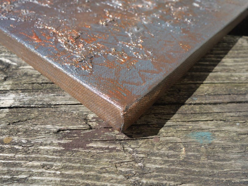 a close-up view of a metal surface with a textured, weathered appearance, resting on a wooden surface.