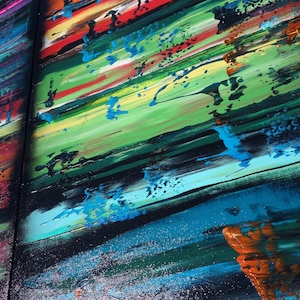 The image is a vibrant, abstract painting with bold, colorful brushstrokes and splatters of paint. The painting features a variety of colors, including red, blue, green, yellow, and orange, creating a lively and dynamic composition. The painting appears to be a large, multi-panel artwork, with the different panels overlapping each other to create a sense of depth and complexity.