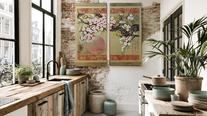 a cozy kitchen with a rustic wooden counter, a sink, and a large potted plant. The walls are adorned with two large paintings featuring floral designs, and the room is illuminated by natural light from the windows.