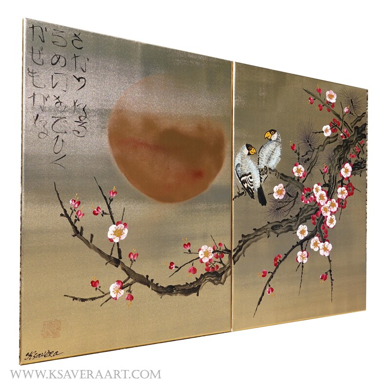 The image is a large painting depicting a scene with two birds perched on a branch adorned with pink and white flowers. The painting is set against a backdrop of a large, reddish-brown circle, which could represent the sun or moon. The artwork is framed by a border, and there is some Japanese text written in the top left corner of the painting.