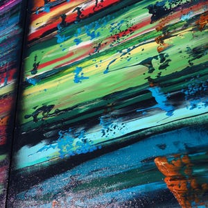 The image is a vibrant, abstract painting with bold, colorful brushstrokes and splatters of paint. The painting features a variety of colors, including red, blue, green, yellow, and orange, creating a lively and dynamic composition. The painting appears to be a large, multi-panel artwork, with the different panels overlapping each other to create a sense of depth and complexity.