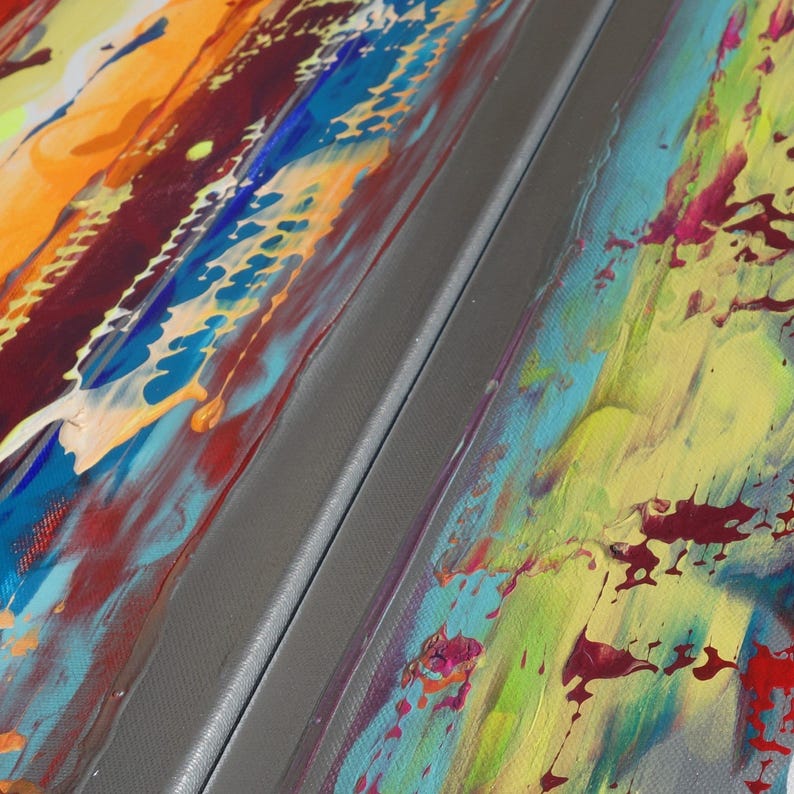 The image is a close-up of a vibrant, abstract painting with bold, colorful brushstrokes and splatters of paint. The painting features a mix of warm and cool colors, creating a dynamic and energetic visual experience.