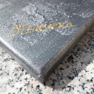a close-up view of a textured surface, possibly a piece of artwork or a fabric, with the word "Ysaya" written in cursive on it.
