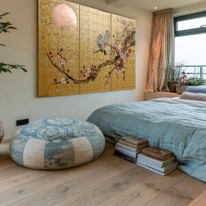 a serene and cozy bedroom with a large bed, a potted plant, and a large window overlooking the ocean. The room has a warm and inviting atmosphere, with a wooden floor and a large painting on the wall.