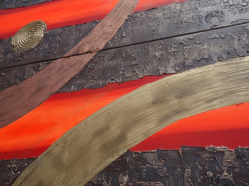 The image is a close-up of a textured surface with a striking contrast of red and black. The red appears to be a warm, fiery hue, while the black has a more muted tone. The surface has a rough, textured appearance, with a few cracks and chips visible. The image is a close-up of a wooden surface, possibly a piece of furniture or a wall, with a metallic or metallic-like texture.
