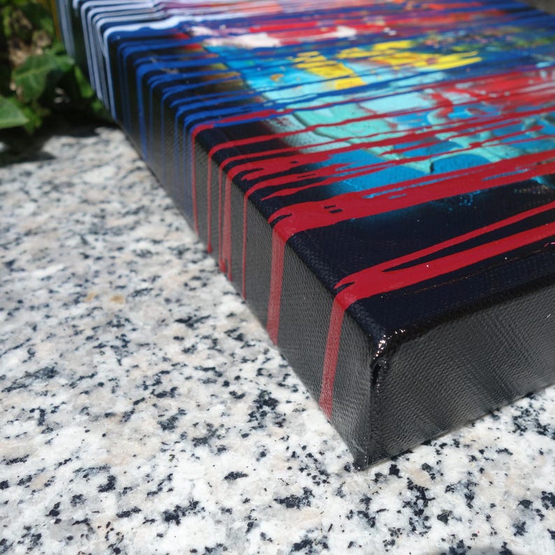 a close-up view of a colorful, abstract painting on a canvas, with bold red and blue stripes on a black background.