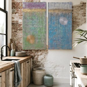 a cozy kitchen with a rustic wooden countertop, a sink, and a large potted plant. The walls are made of exposed brick, and there are two large paintings hanging above the counter. The kitchen also features a window overlooking a city street, and various kitchen accessories and decor items are scattered throughout the space.