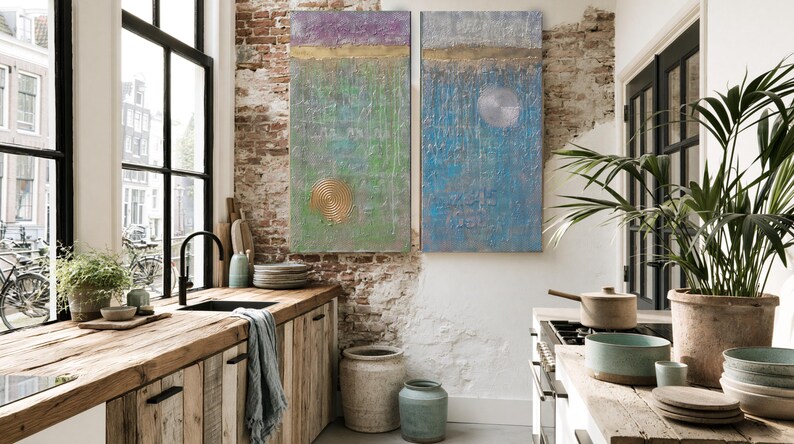 a cozy kitchen with a rustic wooden countertop, a sink, and a large potted plant. The walls are made of exposed brick, and there are two large paintings hanging above the counter. The kitchen also features a window overlooking a city street, and various kitchen accessories and decor items are scattered throughout the space.