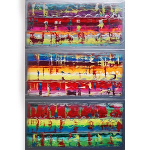 The image is a vibrant, abstract painting composed of three panels, each with a unique color scheme and pattern. The panels are arranged in a vertical format, creating a sense of depth and dimension. The colors used are bold and varied, with shades of red, yellow, green, blue, and purple creating a visually striking and dynamic composition.