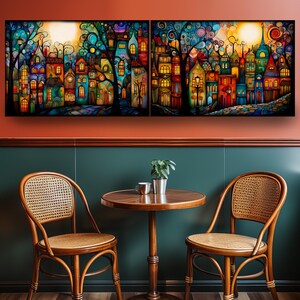 a cozy dining area with a round wooden table and two woven chairs, set against a vibrant, colorful painting of a whimsical town scene.