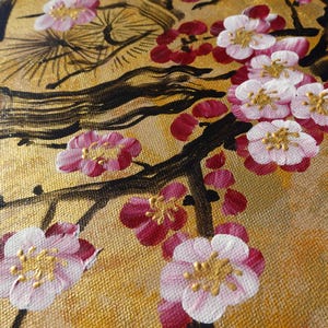 The image is a close-up of a painting featuring a branch with pink and white flowers against a golden background.