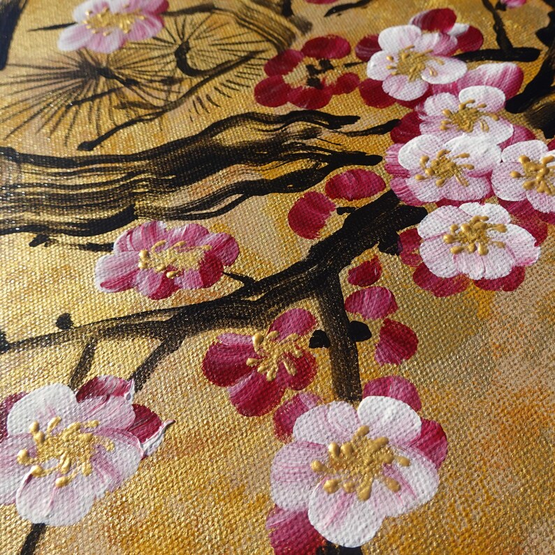 The image is a close-up of a painting featuring a branch with pink and white flowers against a golden background.