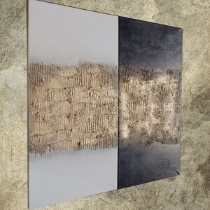 Peut inclure: &OElig;uvre d'art murale abstraite compos&eacute;e de deux panneaux. Un panneau est blanc, l'autre est gris fonc&eacute;. Les deux panneaux pr&eacute;sentent un motif horizontal textur&eacute; de couleur or au centre, cr&eacute;ant un contraste saisissant.