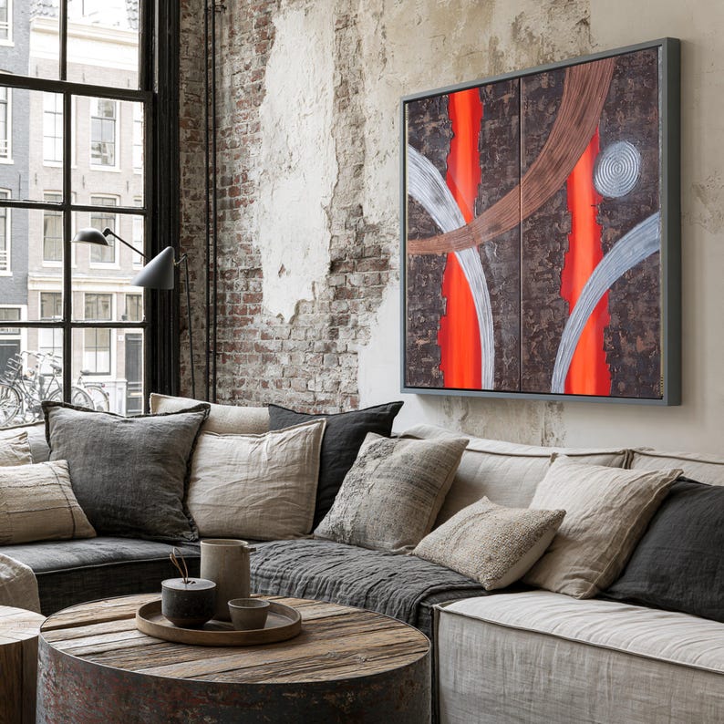 a cozy living room with a large window overlooking a cityscape. The room is furnished with a gray sofa, a wooden coffee table, and a large abstract painting on the wall.