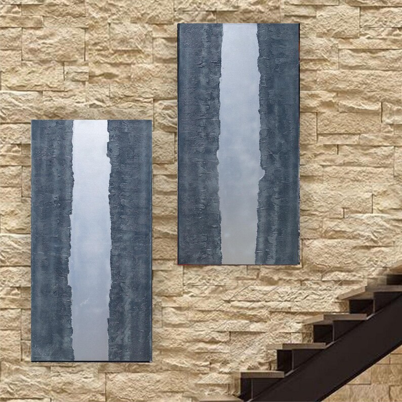 two large rectangular paintings hanging on a brick wall, with a staircase visible in the background.