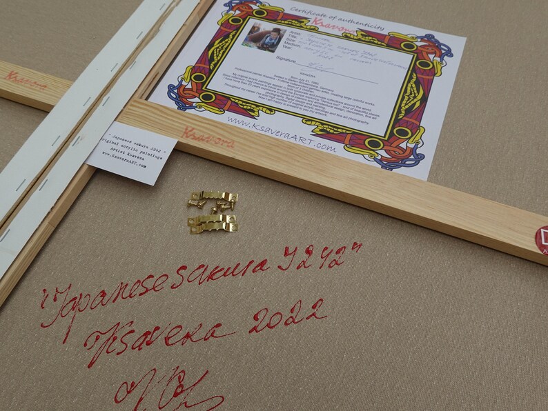 a Japanese calligraphy piece with a certificate of authenticity, a wooden frame, and some gold hardware.