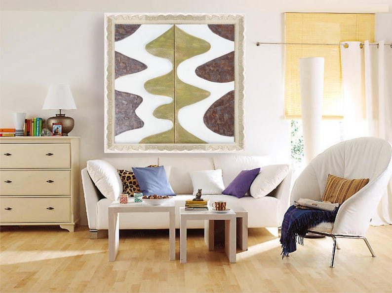 a modern living room with a white sofa, a white armchair, and a white coffee table. Above the sofa, there is a large abstract painting with a white and green color scheme. The room also features a white dresser, a lamp, and a window with yellow blinds.