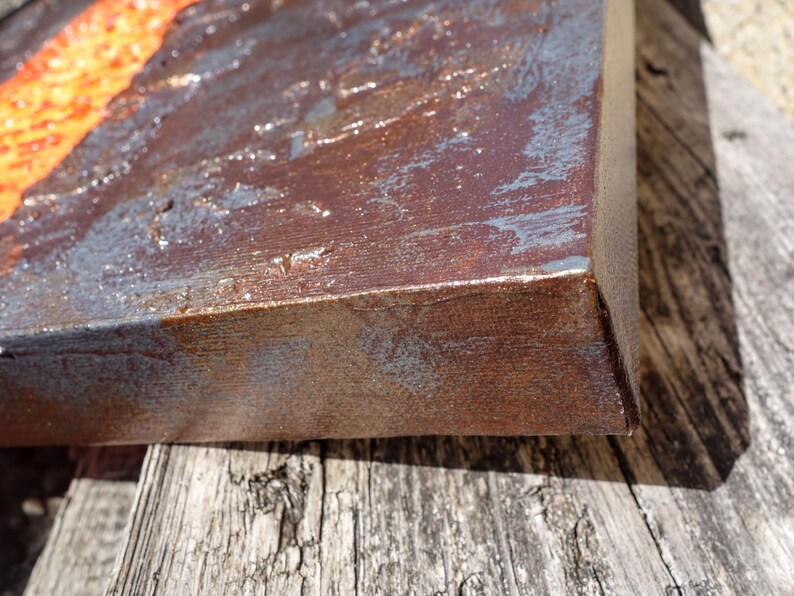 a close-up view of a weathered, rusted metal surface, possibly a piece of furniture or a metal object, with a textured, worn appearance.