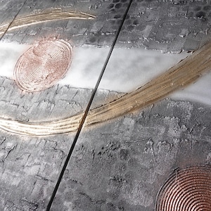 The image is a close-up of a textured surface with a metallic, metallic-looking texture. There are circular patterns and lines on the surface, creating a visually interesting and abstract design.