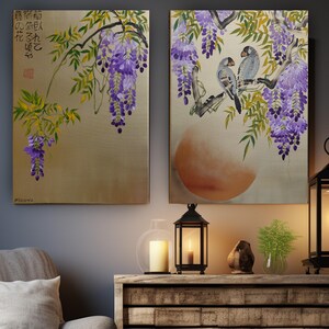 two paintings hanging on a wall, depicting a tree with purple flowers and birds perched on branches. The paintings are set against a wooden shelf, which also holds a lantern and a small plant.