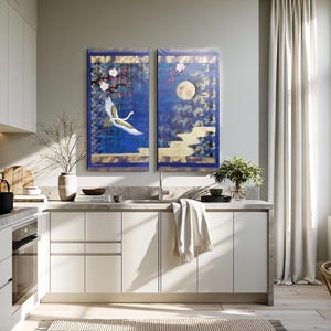a modern, well-lit kitchen with white cabinets, a large window, and a blue and white wall art piece.