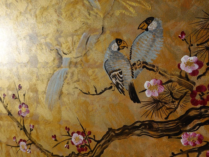 The image is a painting featuring two birds perched on a branch with pink and white flowers. The background is a golden color, and there is a bird flying in the background.