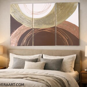a modern bedroom with a large abstract painting on the wall above a bed with white pillows and a gray throw blanket.