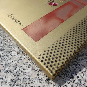 a close-up view of a gold-colored canvas with a red and black patterned texture.