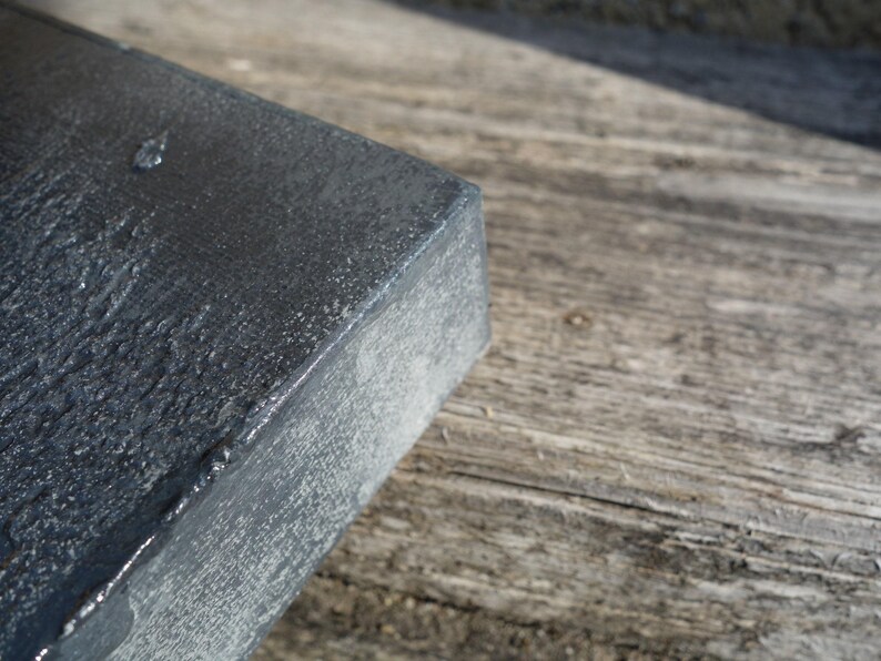 a close-up view of a dark, textured surface, possibly a metal or stone object, resting on a wooden surface.