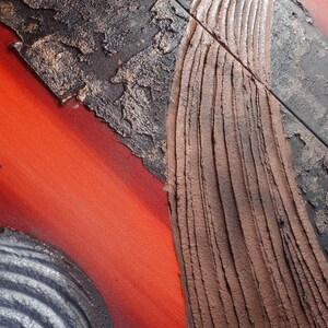 The image is a close-up of a textured surface with a combination of red, brown, and black colors. The surface appears to be a mix of different materials, such as metal and wood, with visible signs of wear and tear.