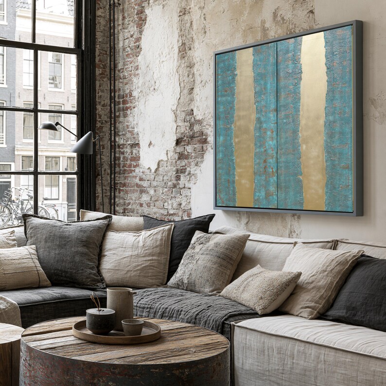 a cozy living room with a large window, a brick wall, and a wooden coffee table. The room has a mix of neutral and vibrant colors, including a blue and gold abstract painting on the wall.