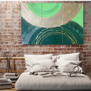 a modern bedroom with a large abstract painting hanging on the brick wall above a bed with white pillows and a white comforter.