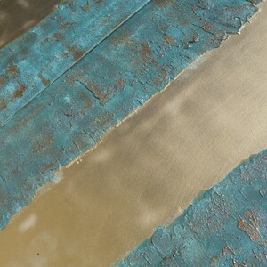 a close-up view of a textured surface with a combination of blue and gold colors. The surface appears to be a mix of paint or material with a textured, weathered appearance.