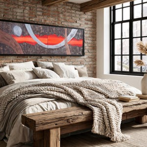 a cozy bedroom with a large bed, a wooden bench, and a brick wall with a large window. The bed is covered in white bedding and has a large blanket draped over it. The wooden bench is positioned next to the bed, and a vase is visible on the windowsill. The brick wall adds a rustic touch to the room, and a large window allows natural light to enter the space.