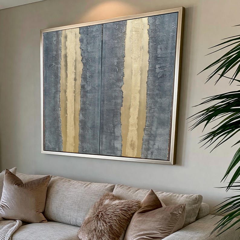 a large abstract painting hanging on a wall above a beige couch with decorative pillows.