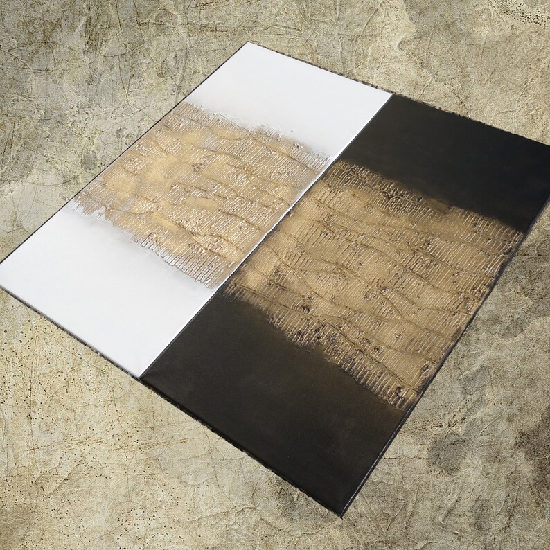 Peut inclure: &OElig;uvre d'art abstraite compos&eacute;e de deux panneaux rectangulaires. Un panneau est blanc avec une bande textur&eacute;e dor&eacute;e, l'autre est noir avec une bande textur&eacute;e dor&eacute;e. L'&oelig;uvre est pr&eacute;sent&eacute;e en angle, soulignant le contraste des couleurs et des textures.