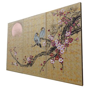 A large, three-panel painting depicting a pair of birds perched on a branch with pink and white flowers. The background features a large, round shape resembling a sun or moon.